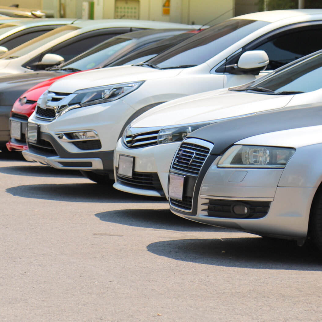 Closeup of front side of  cars parking in outdoor parking lot beside the street  in bright sunny day. The mean of simply transportation in modern world.